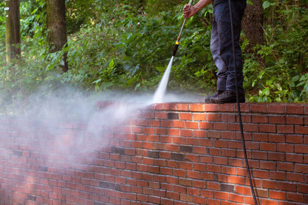 Power washing service cleaning a red brick wall with high pressure water in NYC residential area
