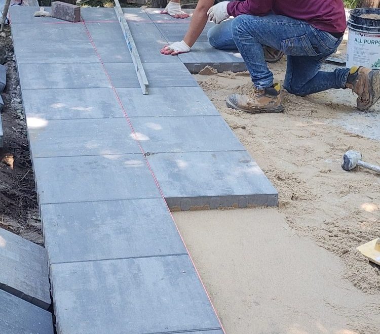 Material services team installing paving stones for a walkway with precision and quality.