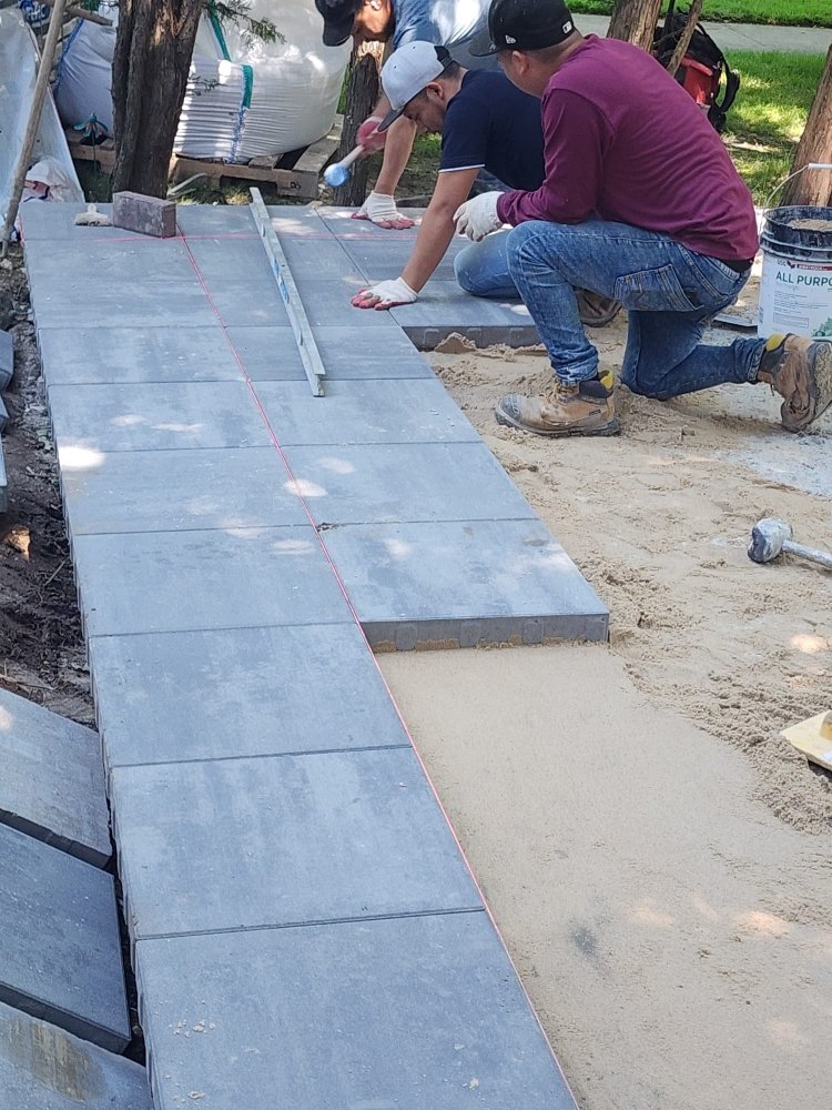 Material services team installing paving stones for a walkway with precision and quality.