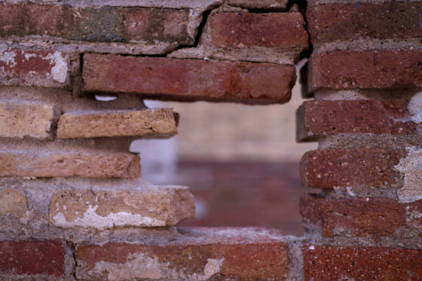 Damaged brick wall with loose mortar joints and cracks visual signs that repointing is urgently needed to prevent further damage.