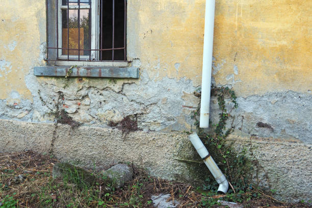 exterior house wall with peeling paint and water damage caused by broken gutter