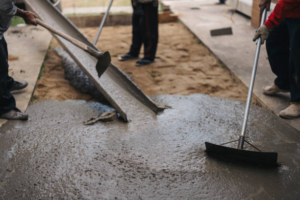 NYC contractors pouring and smoothing fresh concrete on damaged sidewalk area.