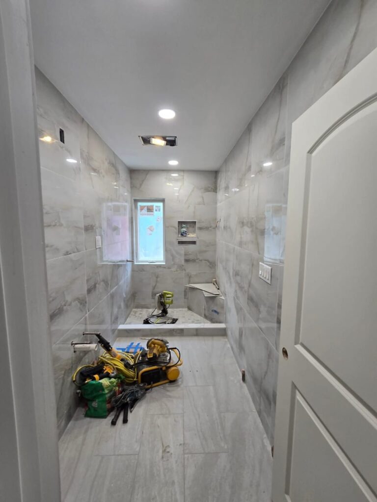 Long, narrow NYC bathroom under renovation showing typical apartment layout and space challenges in older buildings.