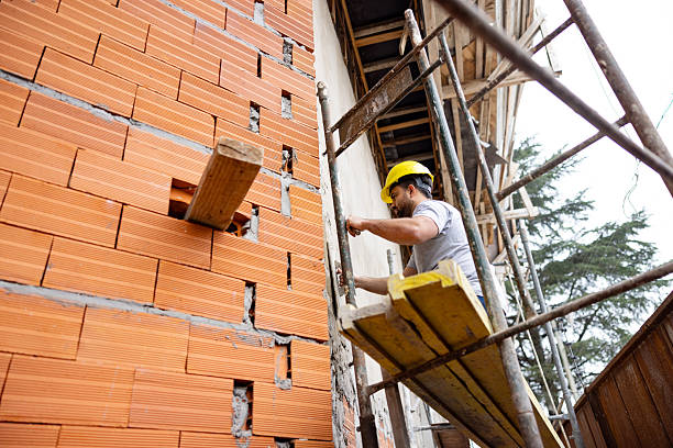 Brick mason working on scaffolding during a commercial build, focused on structure, scale, and long-lasting craftsmanship.