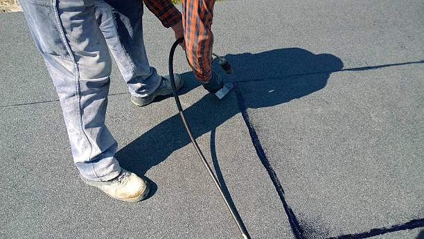 Driveway sealing contractor applying protective layer on asphalt surface in NYC to prevent winter damage