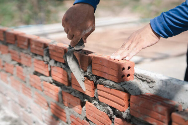 close up hand of bricklayer worker installing bricks on construction site