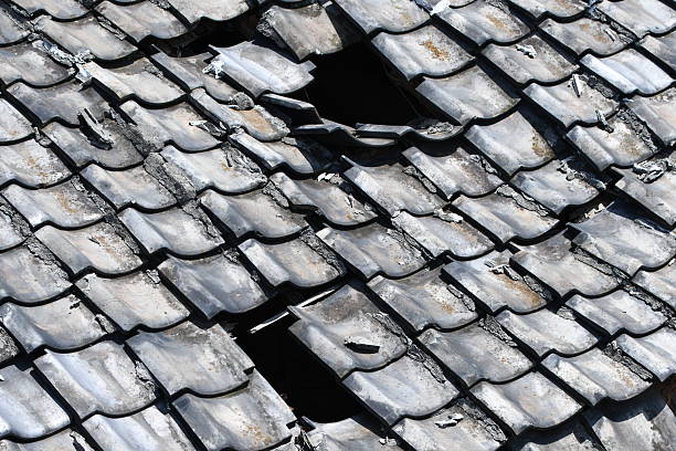 Severely damaged roof with broken and missing shingles indicating urgent need for roofing repair
