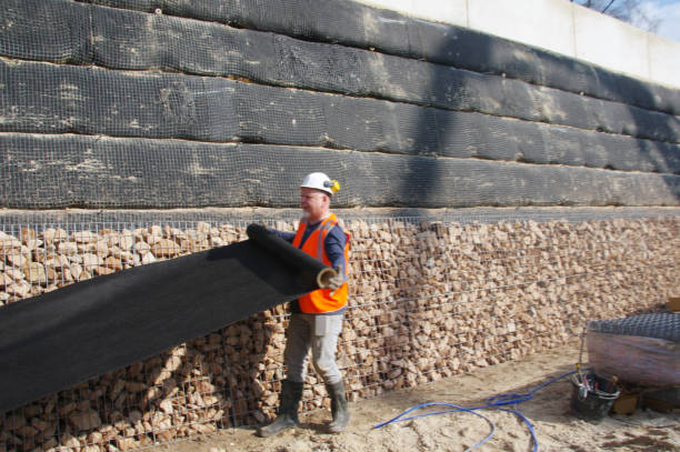 Worker applying AquaDefense Thoroseal waterproofing membrane on wall for long-lasting protection against water seepage and erosion.
