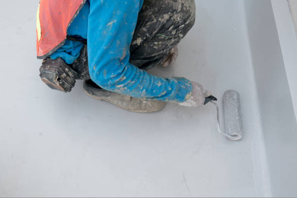 Worker applying AquaGuard Thoroseal waterproofing coating with a roller brush for durable concrete surface protection.