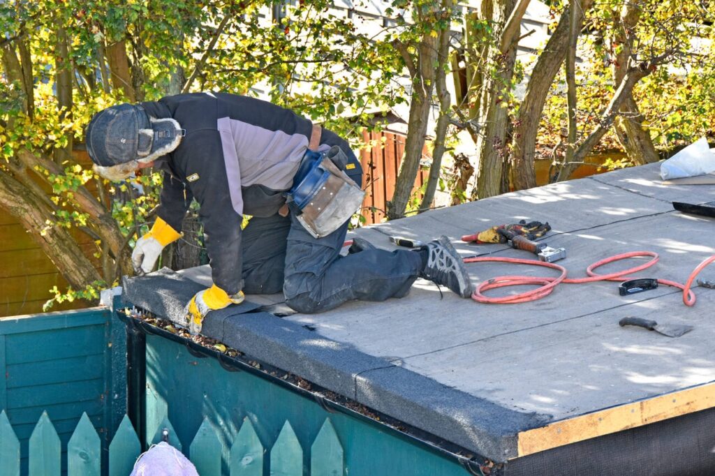 Flat roof repair by professional roofer using tools and materials
