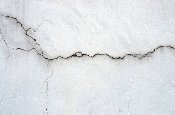 Cracked stucco wall with visible horizontal and branching lines, showing damage before repair.