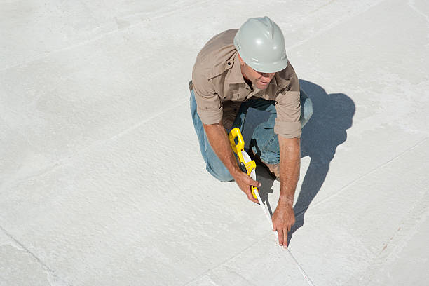 Technician performing TPO roof repair by heat-welding the membrane seams, wearing safety gear on a white thermoplastic roofing surface