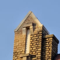 Close-up of a brick parapet wall with triangular top and stone trim