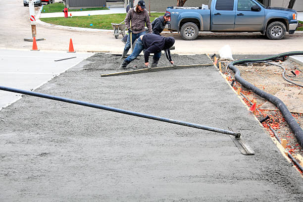 Workers installing a concrete driveway, leveling freshly poured concrete.