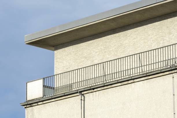 A modern flat-roofed building with a parapet wall and metal railing along the edge for safety