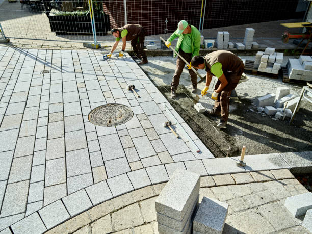 Workers installing concrete paver driveway with interlocking stone blocks