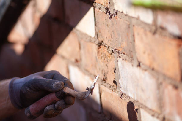 Worker repairing mortar joints during brick repointing and tuckpointing in NYC.