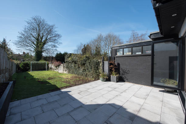 Modern backyard with concrete patio and lawn area on a sunny day.
