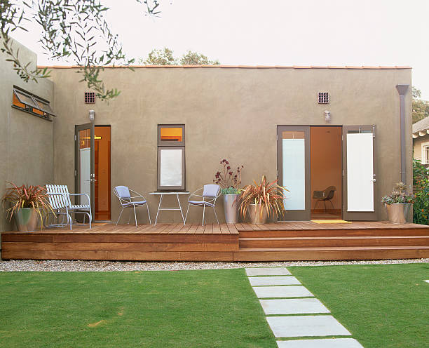 Modern backyard featuring a stylish wood deck with chairs and plants perfect example of deck wood installation in NYC homes.
